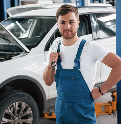Automotive technician standing beside a vehicle in a workshop
