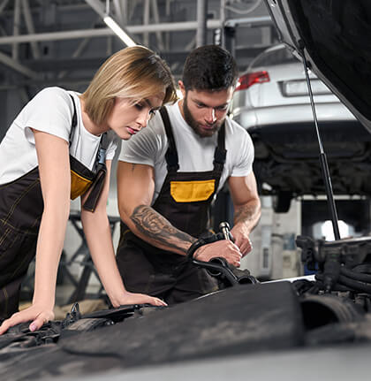 Two automotive technicians inspecting an engine
