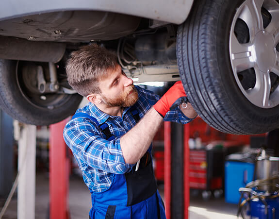 Mechanic inspecting a vehicle wheel and suspension
