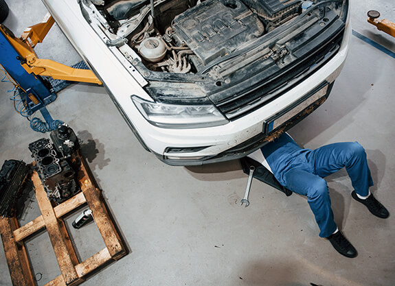Technician working beneath a vehicle in a workshop