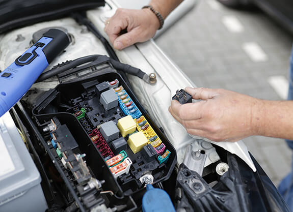 Technician checking a vehicle electrical fuse box