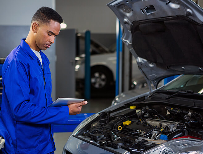 Technician inspecting an engine bay with a tablet