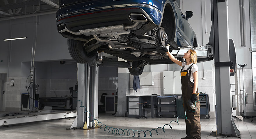 Technician inspecting the underside of a raised vehicle