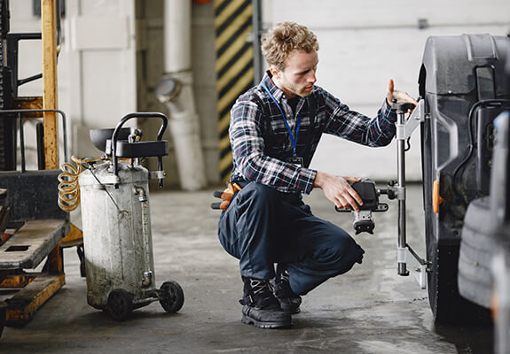 Technician checking wheel alignment equipment