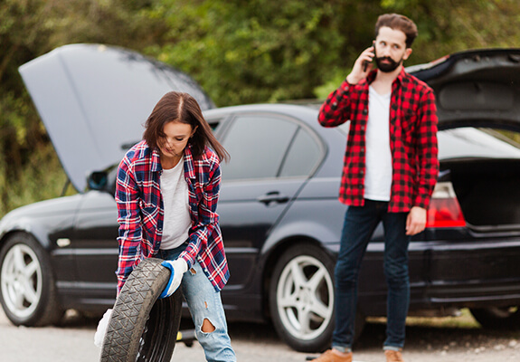 Drivers handling a flat tyre beside a stopped vehicle